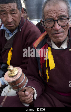 Zanskar, le Jammu-et-Cachemire, en Inde. Deux hommes avec une roue de prière lors d'une puja Bouddhiste. Banque D'Images