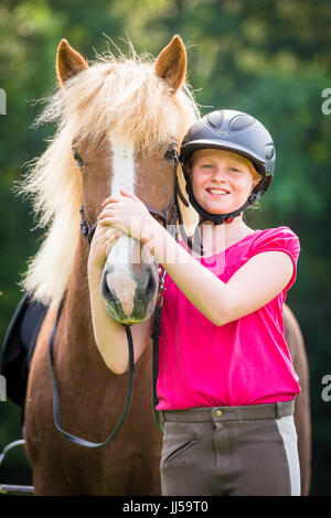 Cheval islandais. Jeune fille debout à côté d'un cheval alezan sur un pré. Allemagne Banque D'Images