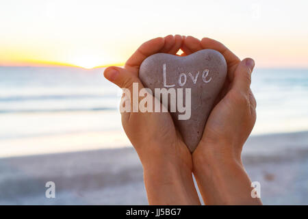 Concept d'amour, mains tenant coeur de sunset beach Banque D'Images