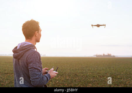 Pilotage de l'homme au coucher du soleil de drones, uav champ arrière-plan technique Banque D'Images