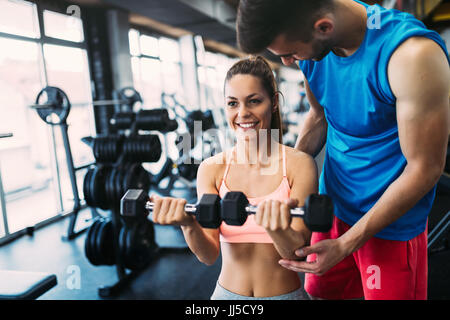 Belle femme faisant des exercices en salle de sport avec un entraîneur personnel Banque D'Images