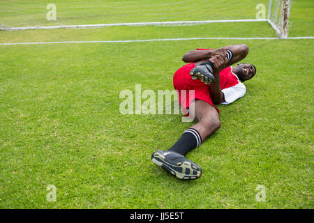 Le joueur de soccer de jeunes hommes souffrant de douleur au genou couché sur terrain de jeu Banque D'Images