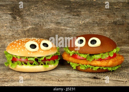 Deux grands yeux drôle avec des hamburgers de poulet et fromage escalope sur fond de bois Banque D'Images