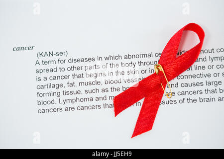 Rouge de ruban de sensibilisation au SIDA sur papier avec texte du cancer Banque D'Images