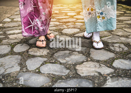 Close up of asian amies portant des kimono et geta chaussures japonaises traditionnelles à pied de cérémonie traditionnelle ou street shopping avec la lumière du soleil i Banque D'Images