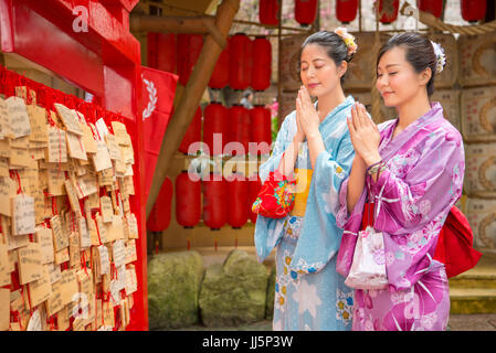Les filles asiatiques portant un kimono traditionnel japon tiens près de l'Ema, Ema sont de petites plaques de bois utilisé pour des rêves par le shintoïsme croient. Amies priez Banque D'Images