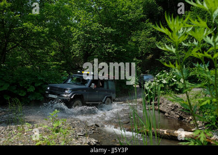 Un véhicule utilitaire sport Suzuki Jimny traverse une route inondée d'eau de boue dans le district de Korsakovsky, au sud-est de l'île de Sakhalin, dans l'océan Pacifique Nord, en Russie Banque D'Images