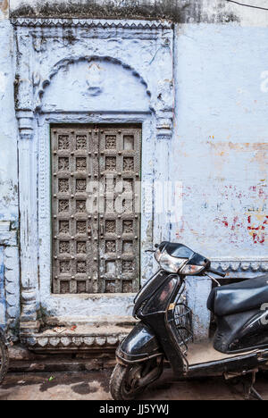 Un scooter est garé en face d'une très vieille porte en bois sculpté au coeur de Varanasi, en Inde. Banque D'Images