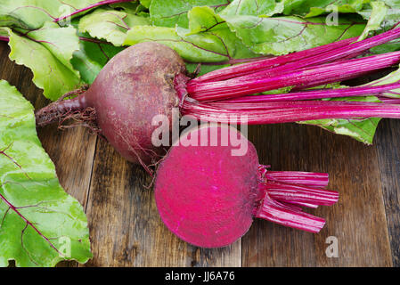 Les betteraves fraîches avec des feuilles sur la table rustique en bois.tout et couper les betteraves Banque D'Images