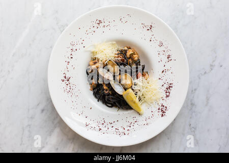 Pâtes noires avec des fruits de mer. Nouilles noir avec les moules, les calmars, les pieuvres avec l'ajout de fromage parmesan. vue d'en haut. Banque D'Images