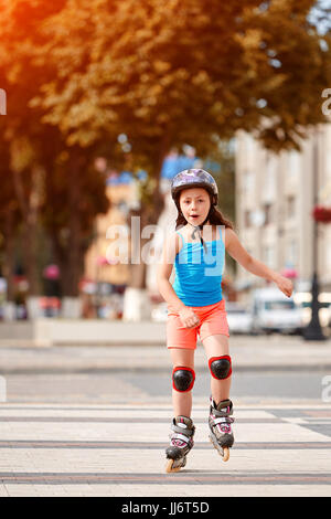 Cute little girl learning to roller skate dans city skate park sur belle journée d'été. Banque D'Images