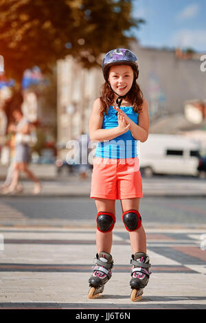 Cute little girl learning to roller skate dans city skate park sur belle journée d'été. Banque D'Images