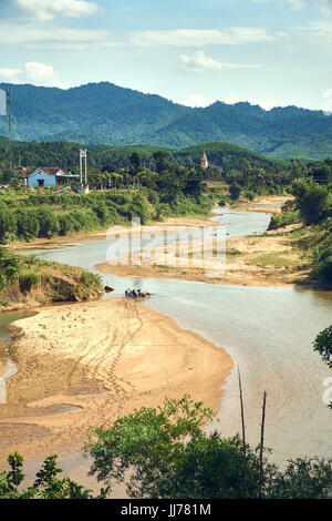 Un troupeau de buffles d'eau décisions empreintes de pas dans la boue dans une rivière dans le parc national de Phong Nha Ke Bang, Vietnam. Avec de grandes montagnes en arrière-plan. Banque D'Images