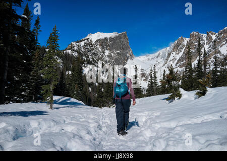 Un female hiker marche le long de la montagne avec de la neige en hiver. Banque D'Images