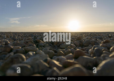 Galets sur Worthing Beach, Plage, Port au coucher du soleil. Banque D'Images