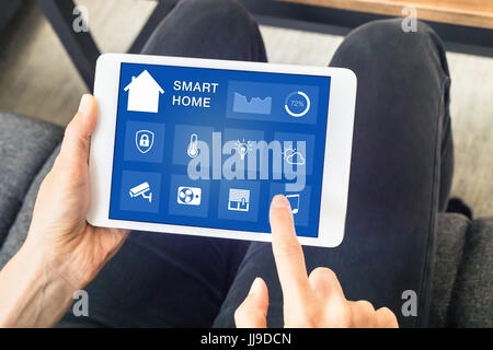 Close-up de mains à l'aide de smart home automation assistant sur un écran d'ordinateur tablette numérique pour contrôler les appareils connectés dans la chambre Banque D'Images