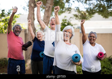 Cheerful multi-ethnic seniors avec bras levés de tapis d'exercice comptable at park Banque D'Images