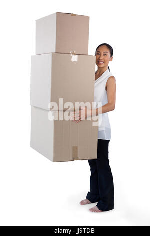 Portrait of businesswoman carrying stack de boîtes de carton tout en standing against white background Banque D'Images