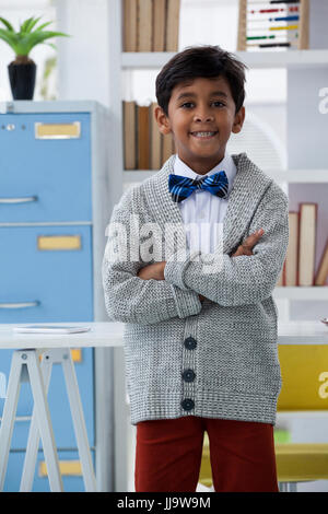 Portrait of businessman with arms crossed standing by desk in office Banque D'Images