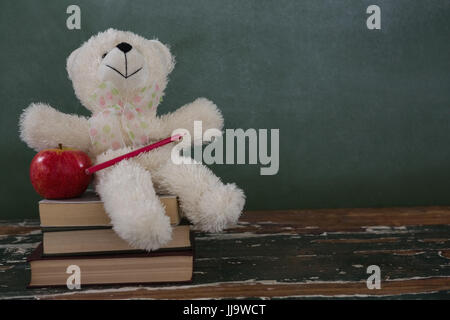 Close-up de l'ours en peluche, crayon et apple sur pile de livres Banque D'Images