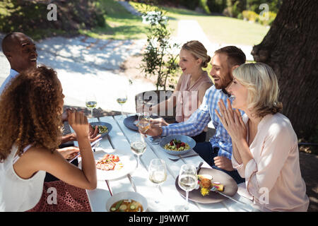 Happy friends en interaction les uns avec les autres tout en ayant des repas au restaurant Banque D'Images