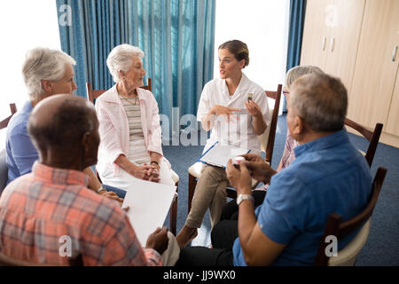 High angle view of female doctor talking to seniors tout en étant assis sur des chaises à la maison de retraite Banque D'Images