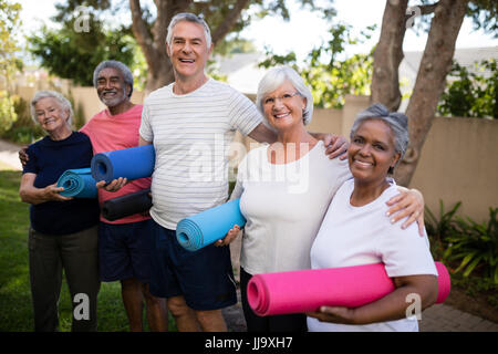 Portrait de professionnels multi-ethnic friends réalisation de tapis d'exercice tout en se tenant au parc Banque D'Images