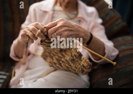 Portrait of senior woman knitting wool, assis sur un canapé à la maison de retraite Banque D'Images