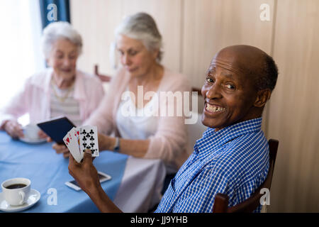 Portrait of smiling man jouer aux cartes avec des amis tandis que le café à table Banque D'Images