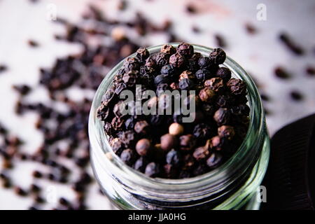 Poivre épicé dans un bocal en verre sur un fond de bois. Banque D'Images