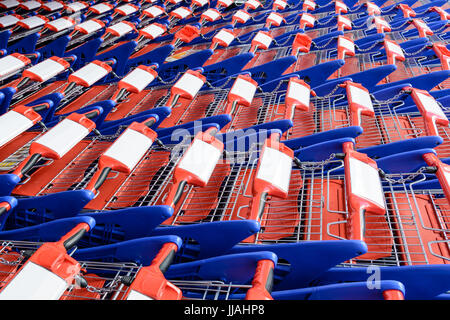 Les chariots rouges et bleus sont imbriqués les uns dans les autres sur plusieurs lignes. Banque D'Images