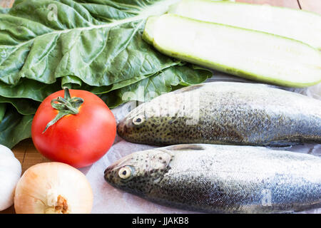 Truites fraîches avec des légumes sur une table. Banque D'Images