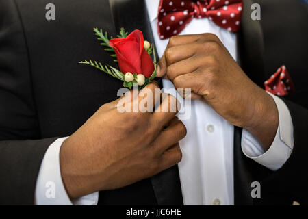 Les axes des ados sa boutonnière rose costume officiel pour obtenir habillé et prêt pour le prom. Banque D'Images