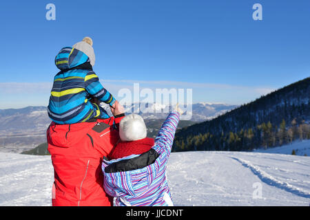 Père, mère et enfants s'amusent et jouent sur l'hiver enneigé à pied dans la nature. Banque D'Images