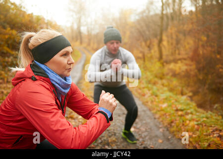 Athletic couple doing squats entre forest Banque D'Images