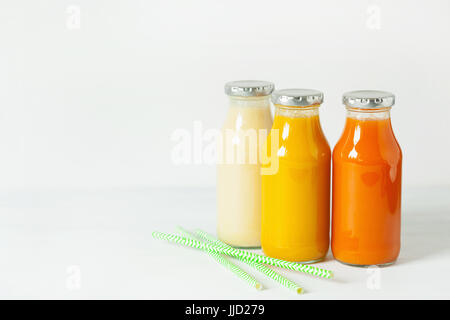 Des smoothies de fruits et légumes dans des bocaux en verre, orange carotte banane mangue ananas Banque D'Images