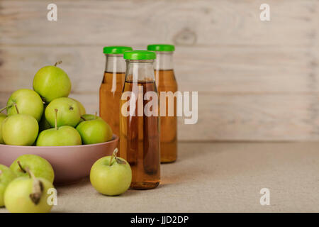 La pomme verte dans une plaque de lilas et une bouteille de jus de pomme en bois sur un fond clair. Focus sélectif. Banque D'Images