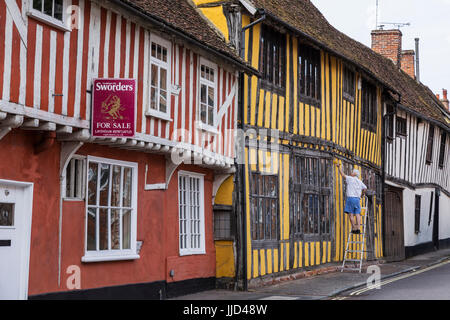 Rangée de bâtiments colorés en Half-Timbered la rue Water, Lavenham avec l'homme sur la peinture Escabeaux Banque D'Images