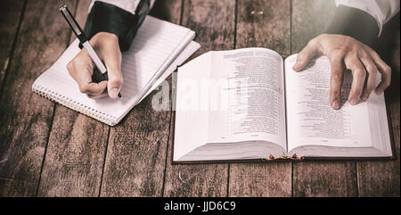 Femme avec bible et écrit sur le bloc-notes au tableau en bois Banque D'Images