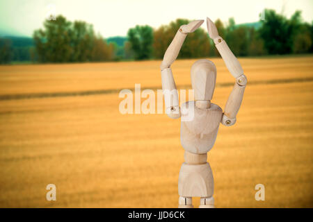 Figurine 3d en bois debout avec les mains posées contre l'avis de prairies Banque D'Images