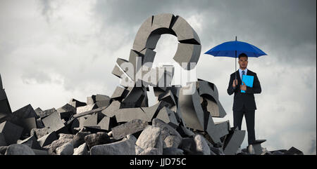 Portrait of serious businessman holding blue umbrella et dossier contre full frame shot of sky Banque D'Images