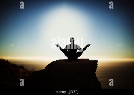 Silhouette businessman meditating contre vue panoramique de montagne par mer contre sky Banque D'Images