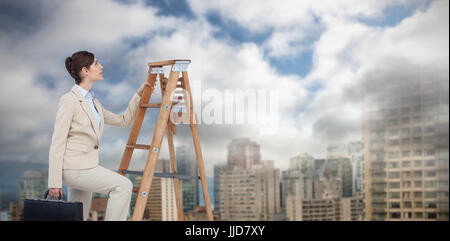 Businesswoman climbing career ladder with briefcase contre tours en ville Banque D'Images