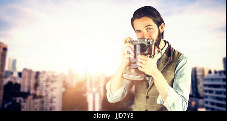 Portrait of man photographing par vintage camera contre ville contre le ciel bleu Banque D'Images