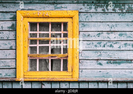 Petite fenêtre jaune vert sur le mur en bois de la maison abandonnée Banque D'Images