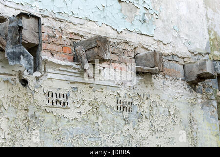 Vieilles poutres en bois au mur de briques en ruine de l'immeuble abandonné. décollement de la peinture. Banque D'Images