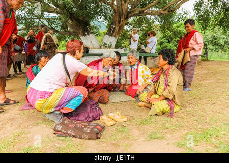 Thimphu, Bhoutan - 15 septembre 2016 : Caucasian woman montrant des images sur son mobile de Bhoutanais en vêtements traditionnels assis dans un jardin en Banque D'Images