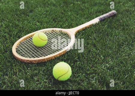 Raquette de tennis en bois vintage sur l'herbe avec des boules Banque D'Images