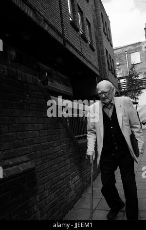 Un homme âgé avec bâton de marche marche lentement dans une rue d'Islington, Londres Banque D'Images