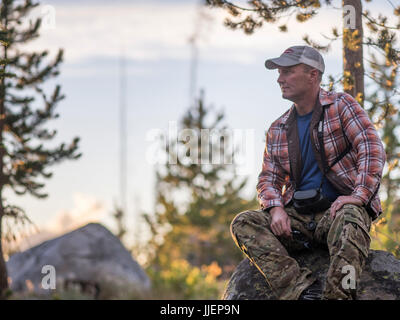 Photographie de l'homme avec les jumelles reposant tout en étant assis sur le rocher après la randonnée, McCall, California, USA Banque D'Images